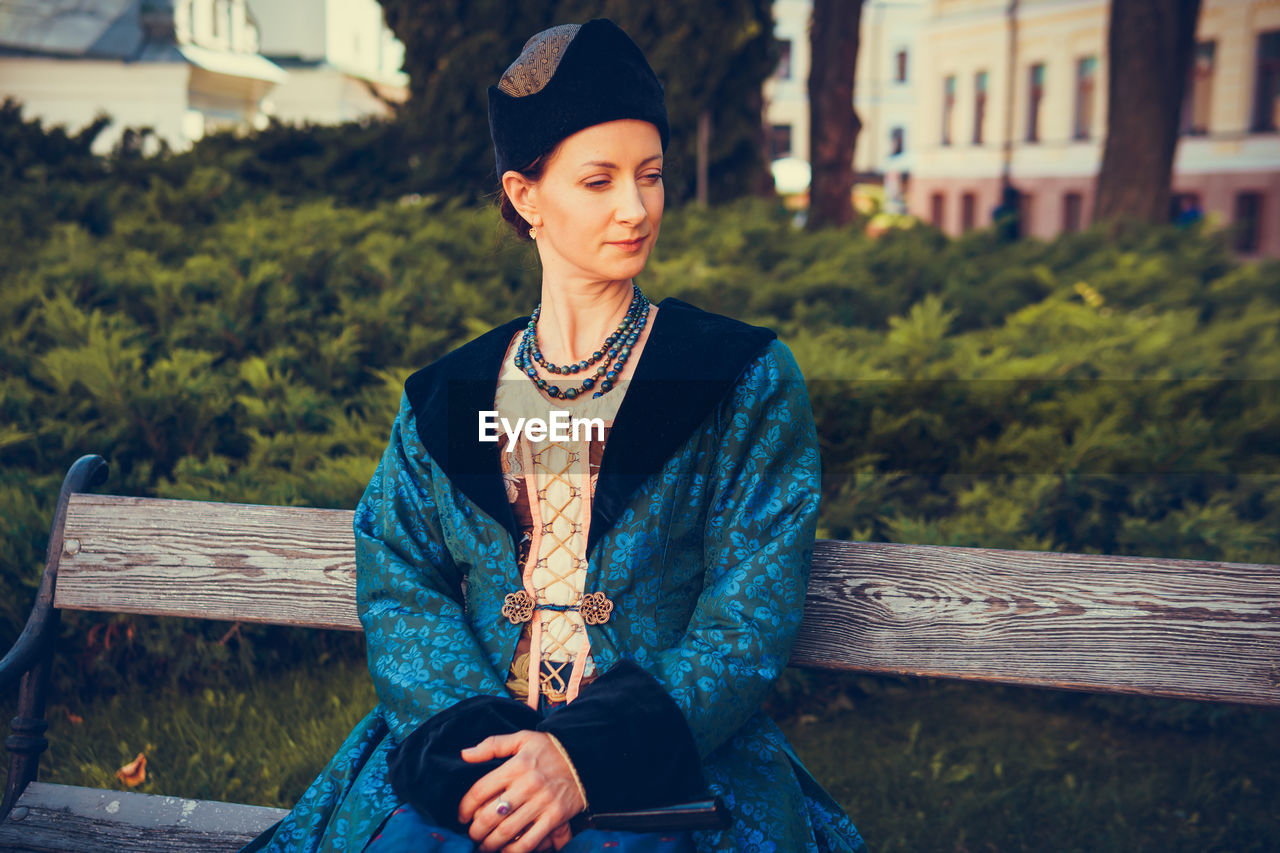 PORTRAIT OF BEAUTIFUL WOMAN SITTING ON BENCH