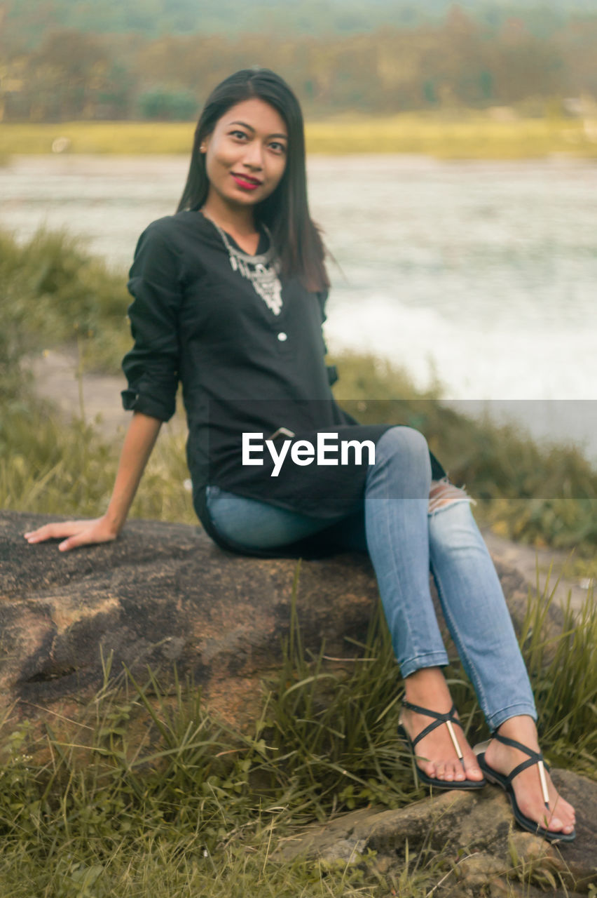 Portrait of young woman sitting on rock