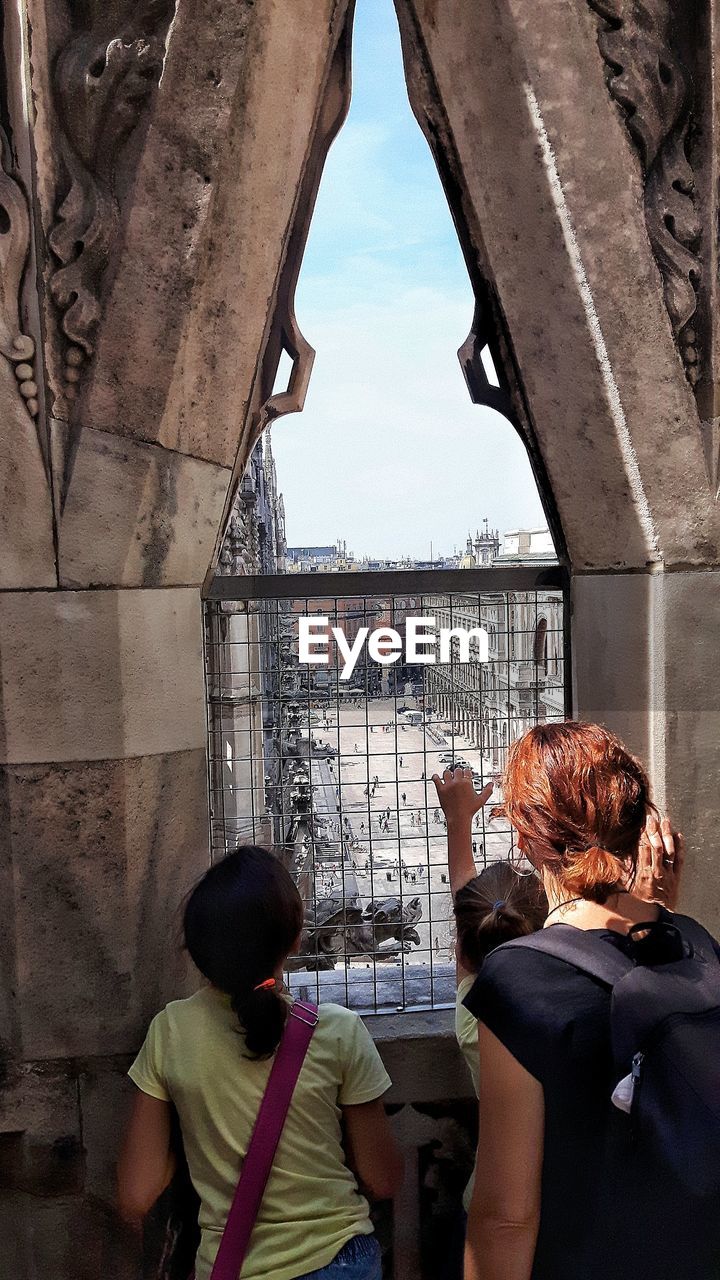 Rear view of people standing against sky in city