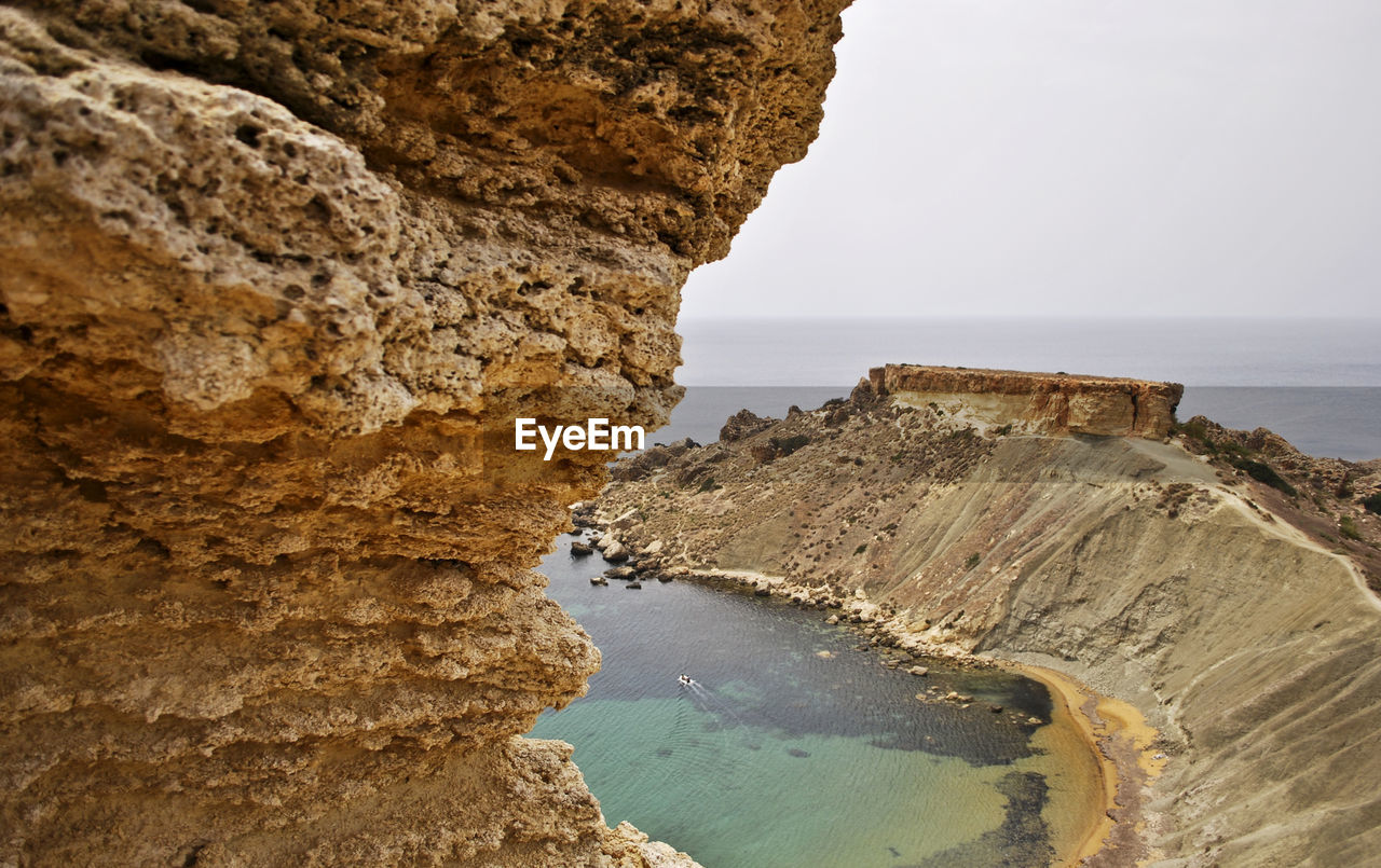 Rock formations on sea shore against sky