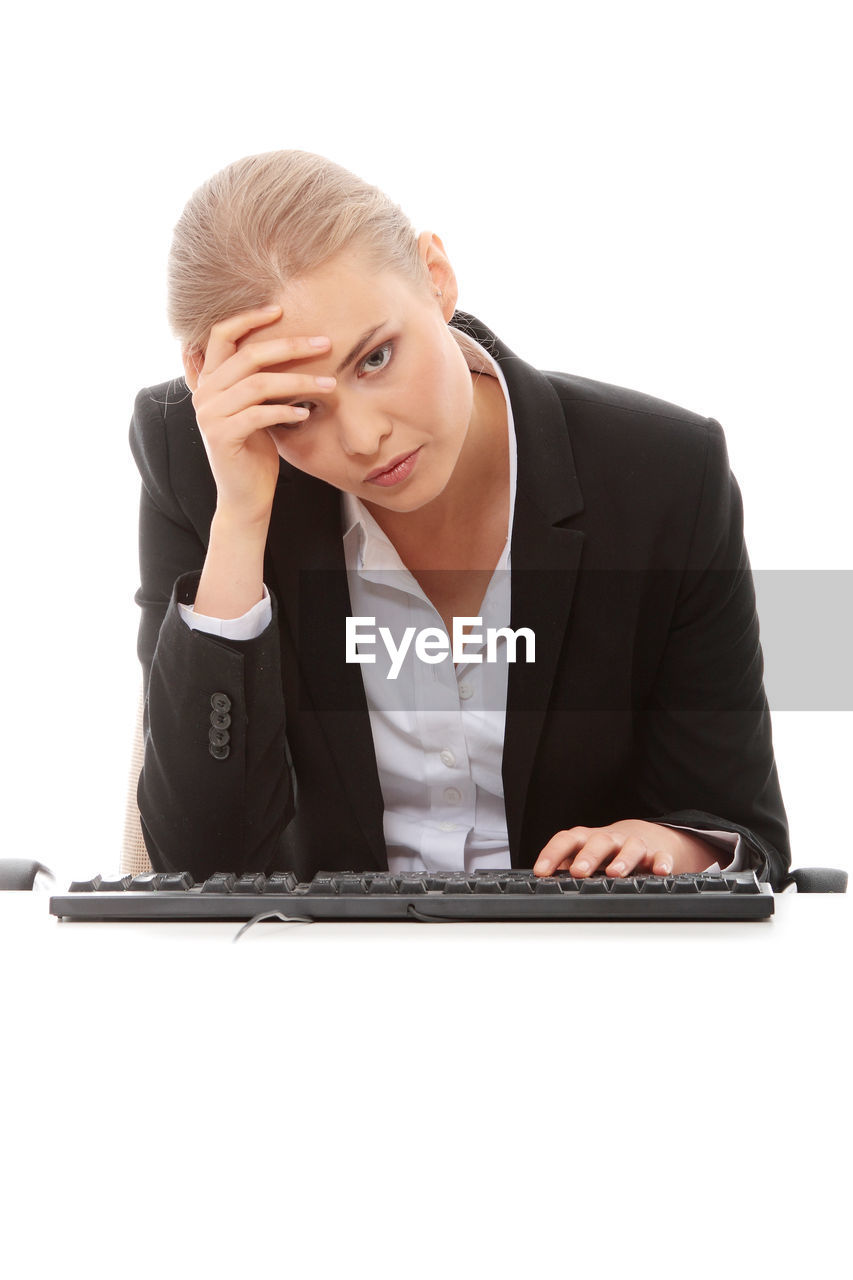 Businesswoman working at desk against white background