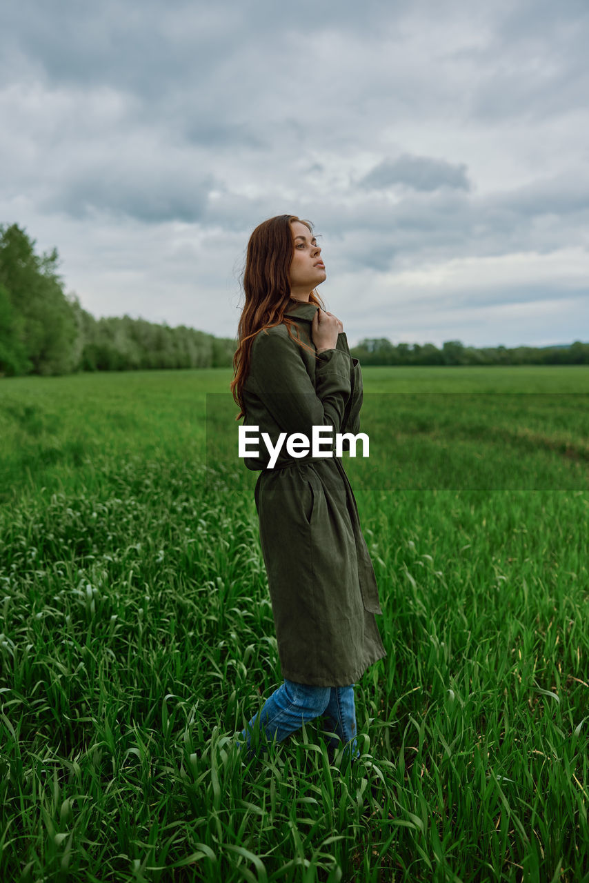 rear view of woman walking on field against sky