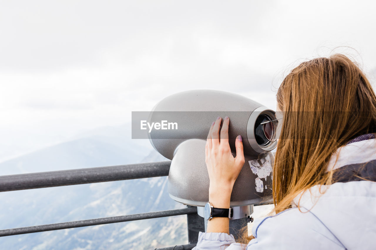 Young women looks at mountain views in binoculars from observation