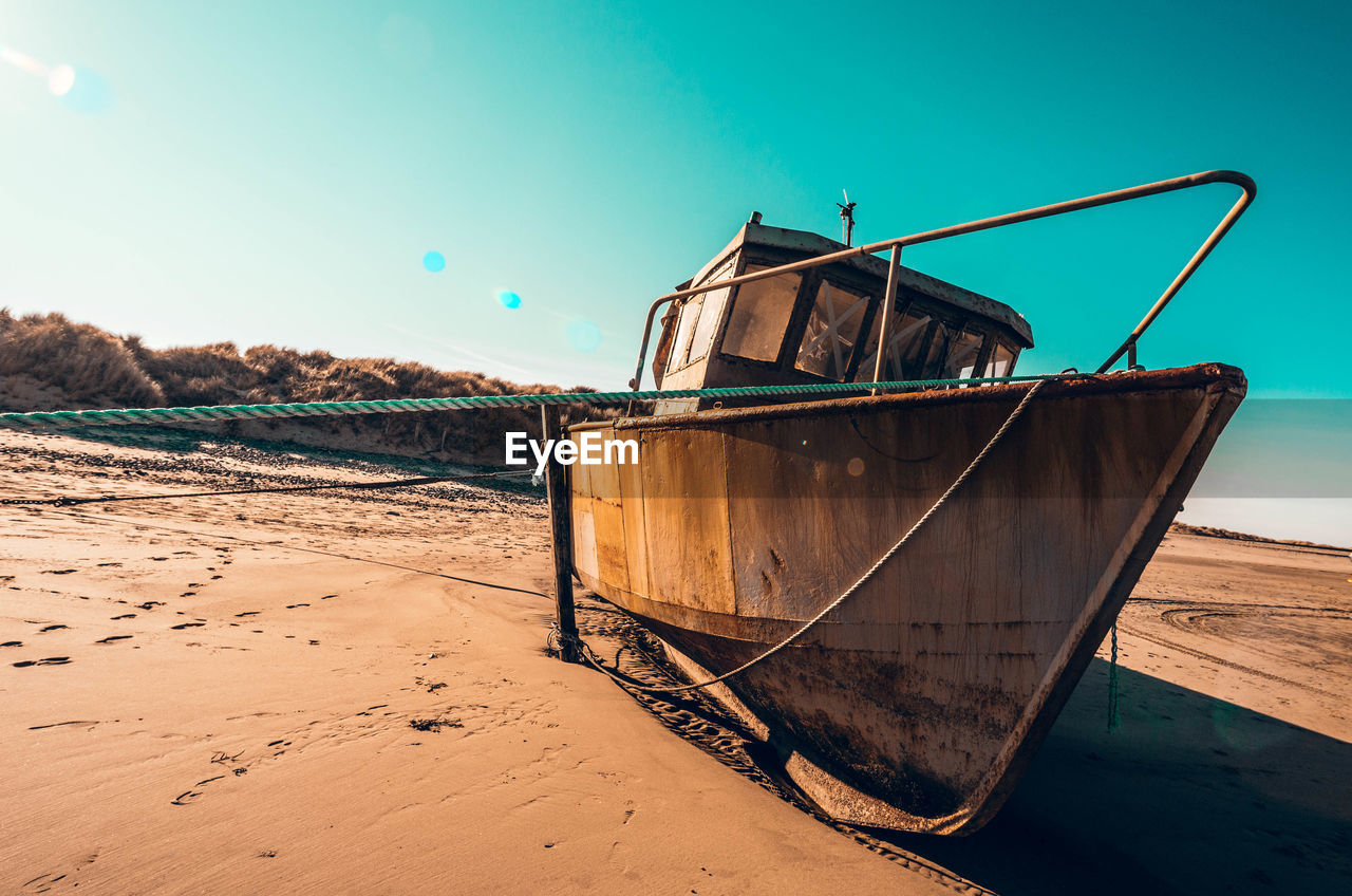 Abandoned ship moored on beach against clear sky