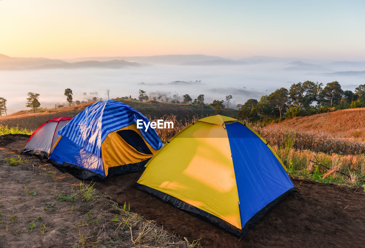 TENT ON FIELD AGAINST SKY AT SUNSET