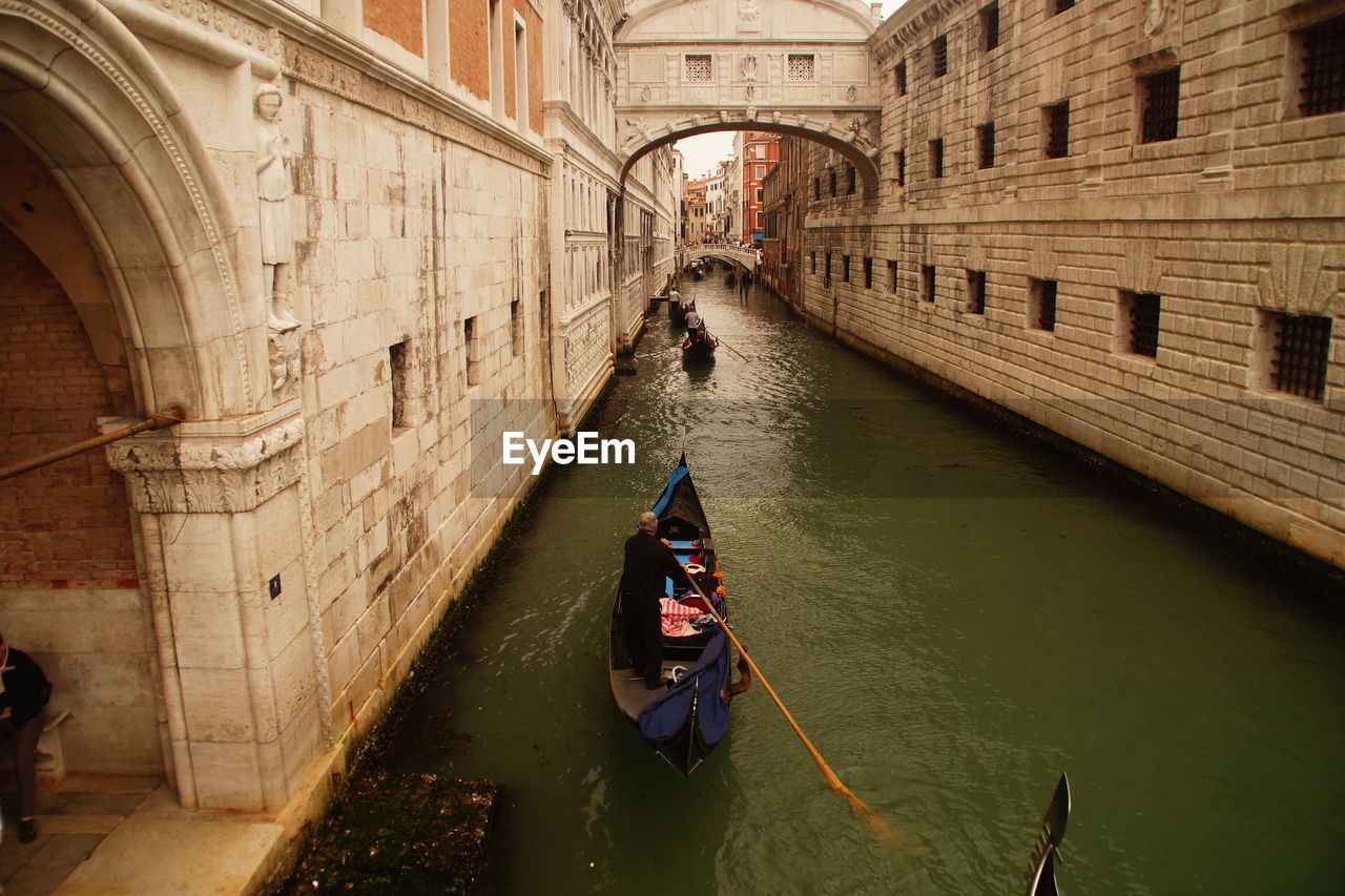 High angle view of man in gondola on canal amidst buildings