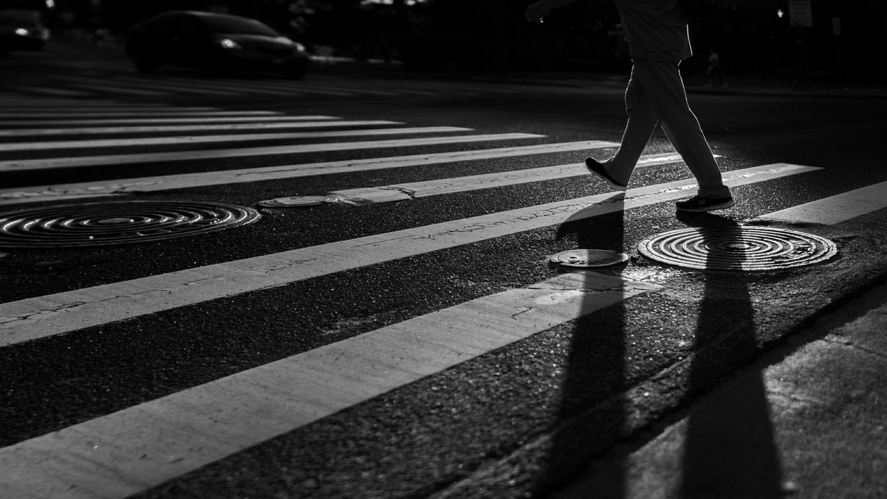 Low section shot of man walking across zebra crossing