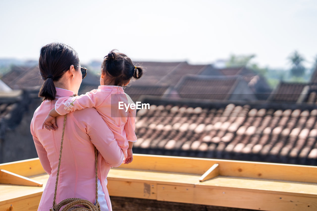 Mother and daughter with vietnam culture traditional dress standing at the rooftop in hoi an.