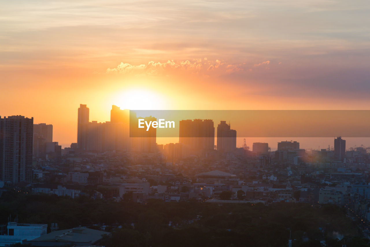 Buildings in city against sky during sunset