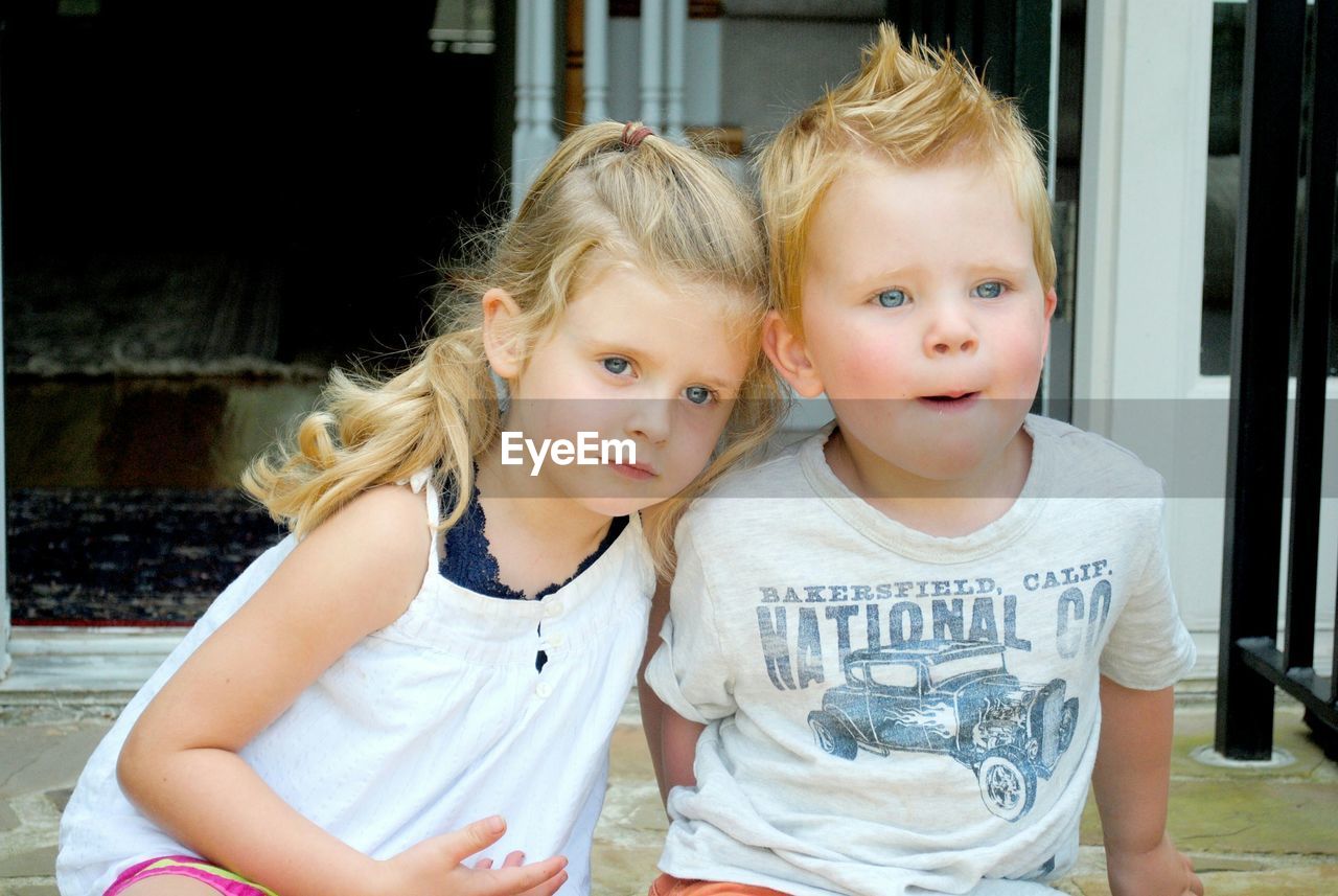 Cute siblings looking away sitting on doorway