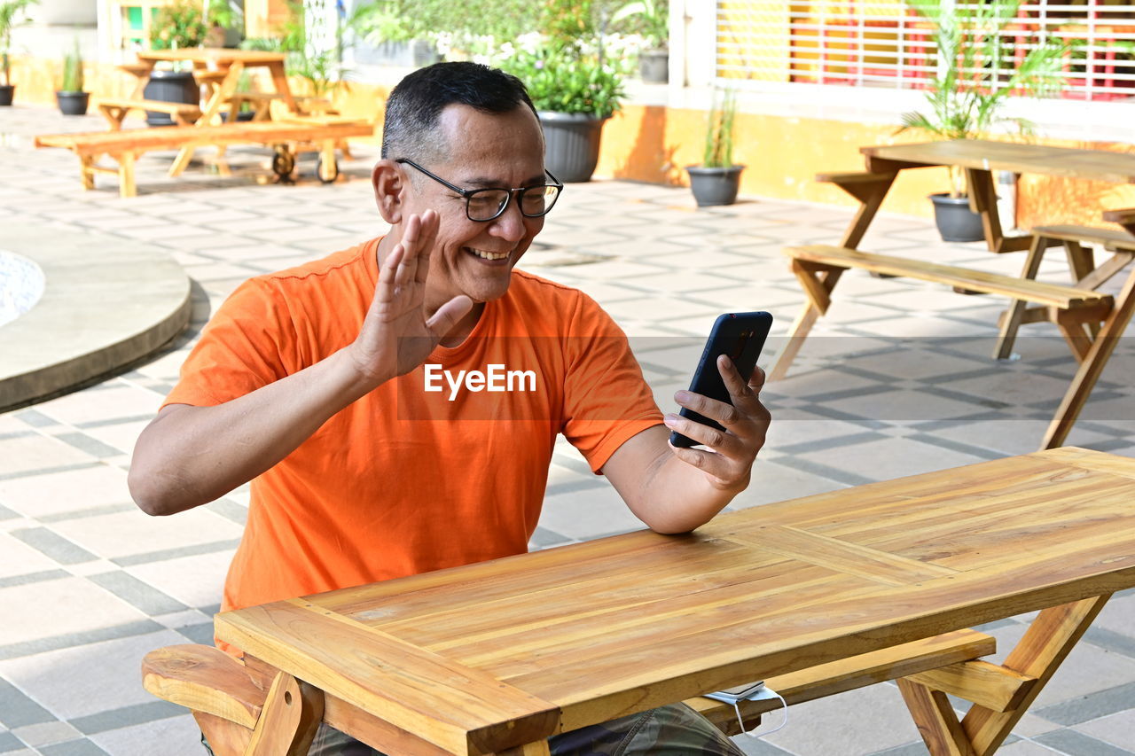 Man using mobile phone while sitting on table