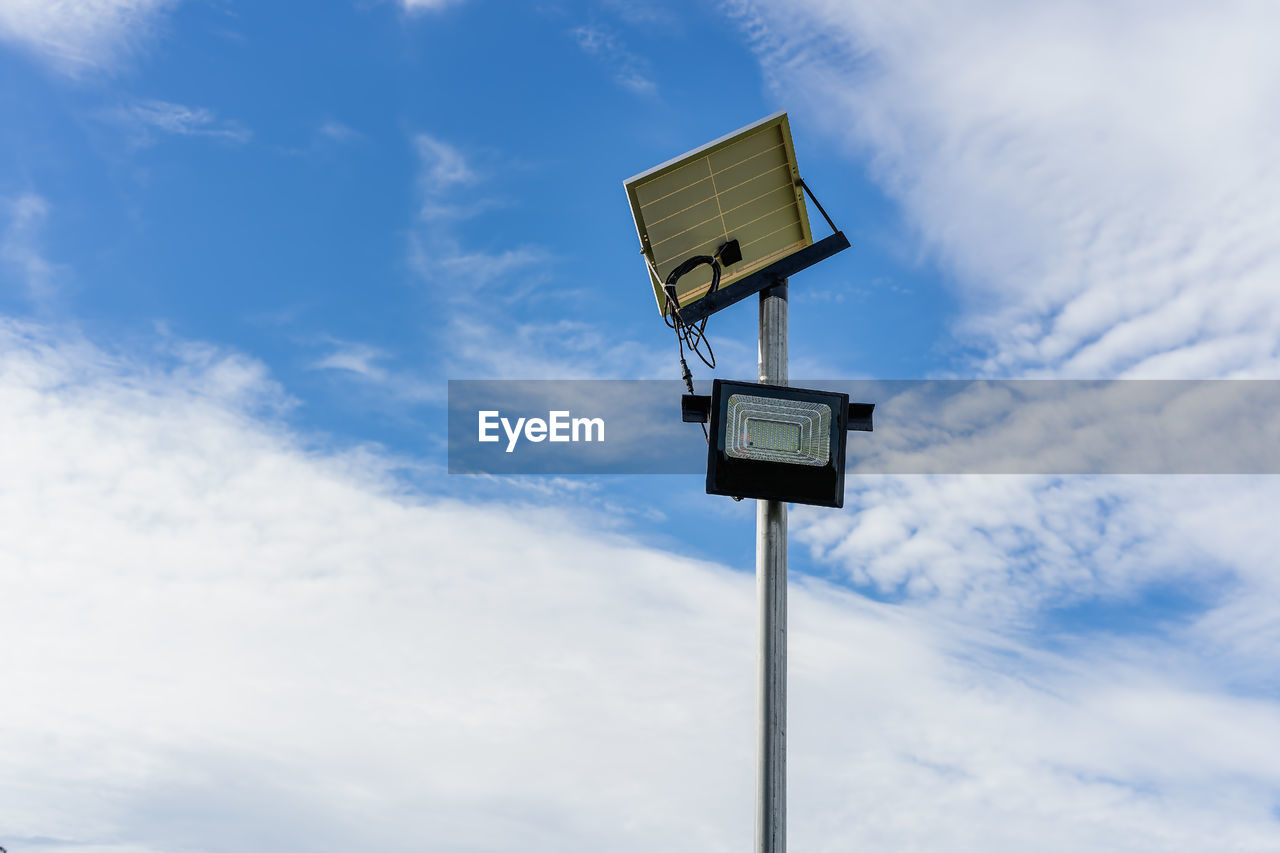 Small solar panel for light in street or park with white clouds and blue sky. 