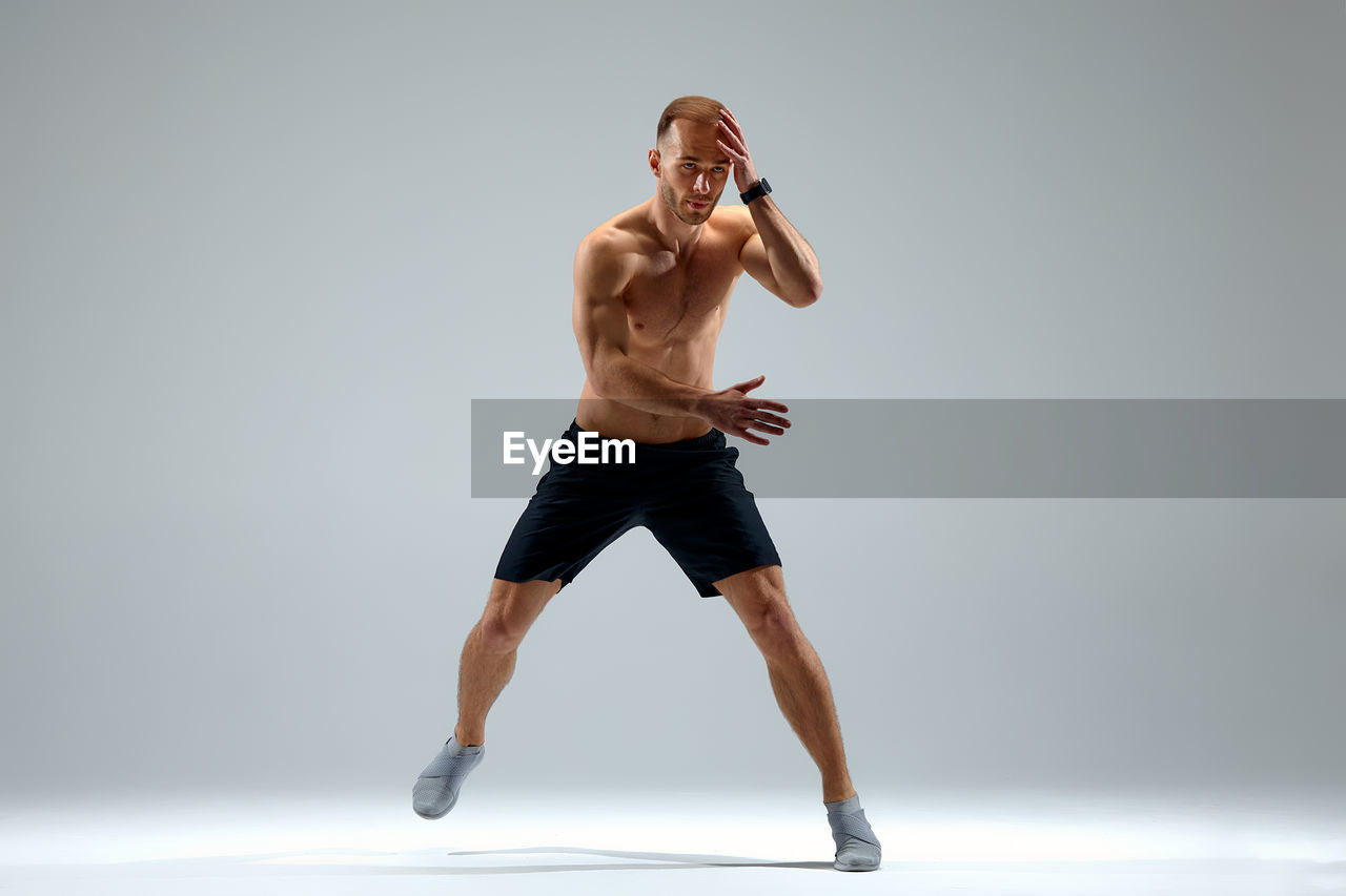 side view of woman exercising against white background