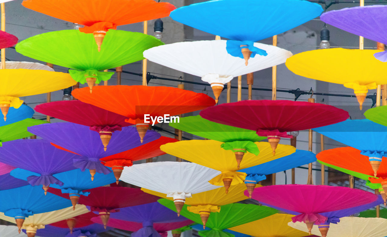 LOW ANGLE VIEW OF MULTI COLORED LANTERNS HANGING IN TRADITIONAL