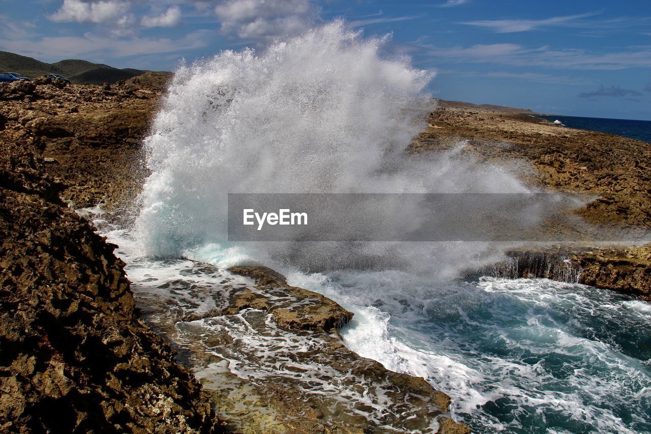 body of water, water, motion, sea, wave, rock, coast, beauty in nature, shore, power in nature, nature, wind wave, blowhole, ocean, scenics - nature, breaking, splashing, sky, land, no people, sports, hitting, cloud, water sports, environment, outdoors, terrain, cliff, geology, landscape, beach, rock formation, day, travel destinations, force