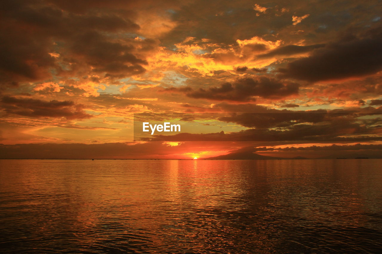 Scenic view of sea against dramatic sky during sunset