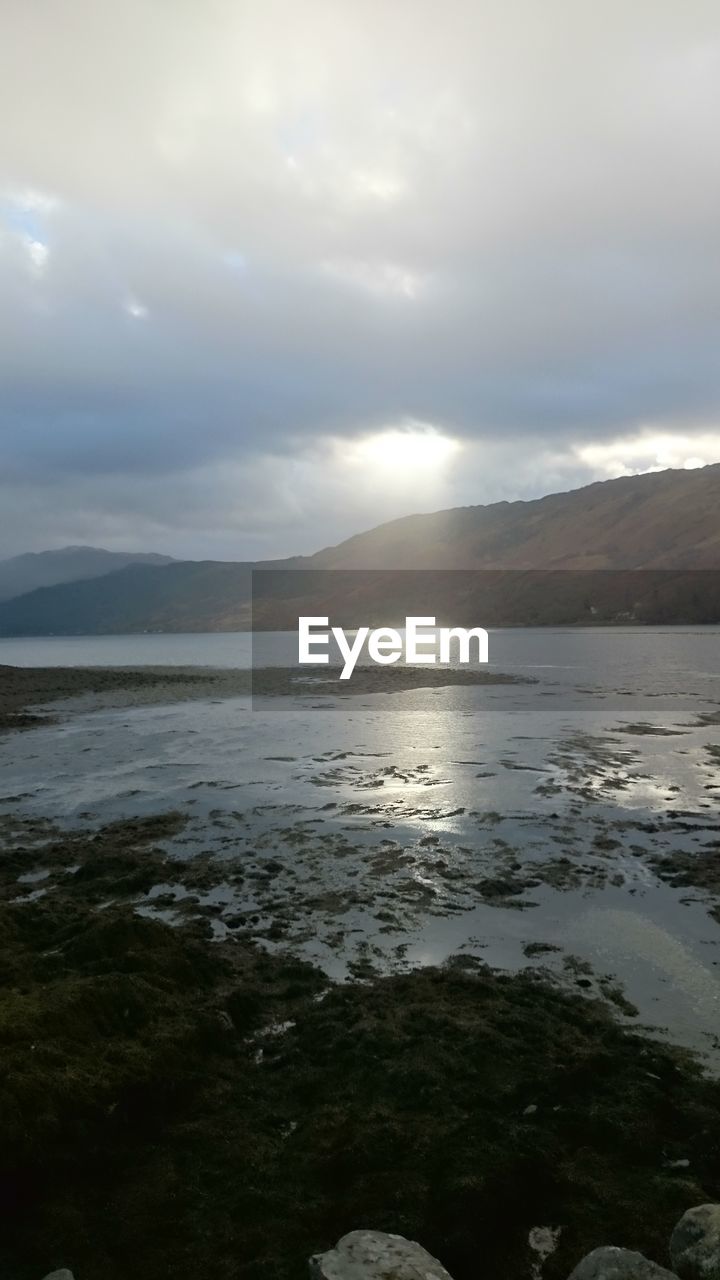 SCENIC VIEW OF SEA AGAINST MOUNTAINS