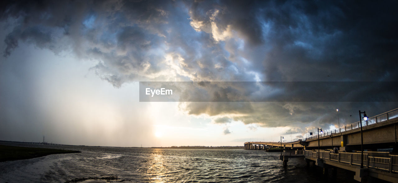 Bridge over sea against cloudy sky