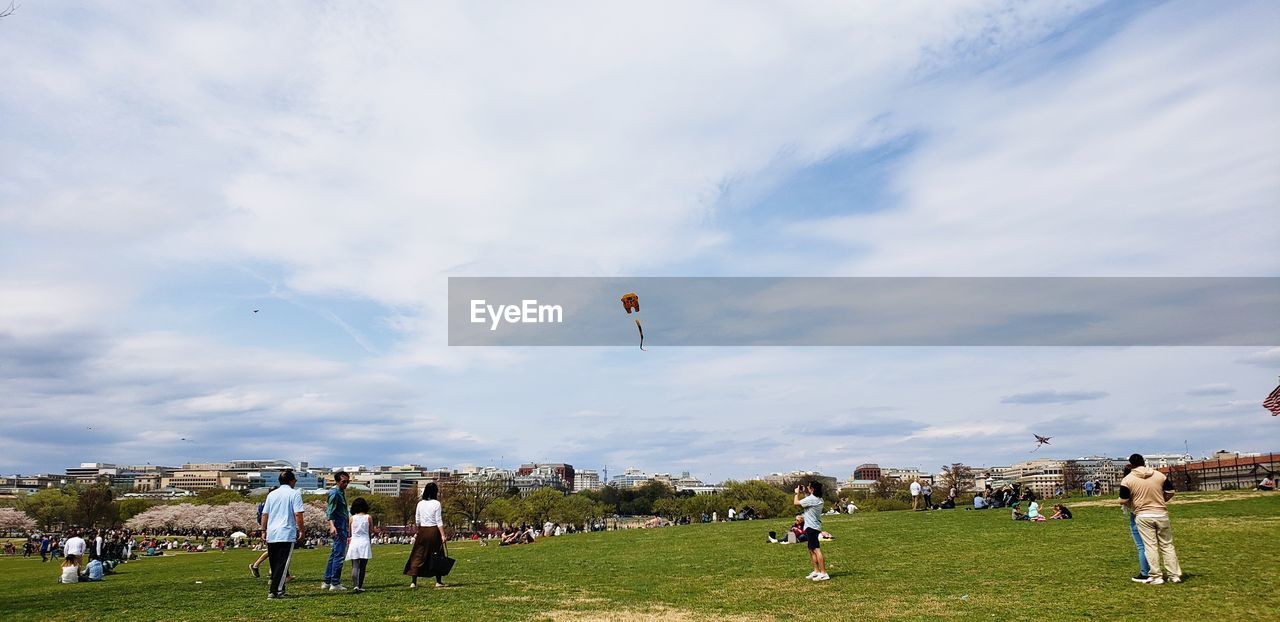 GROUP OF PEOPLE ON FIELD AGAINST THE SKY