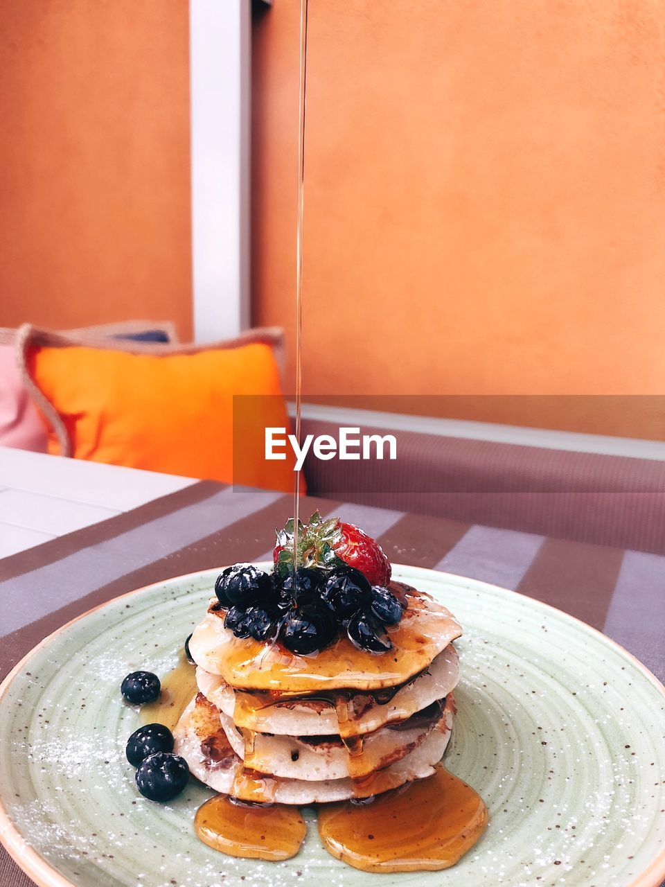 Syrup being poured on pancakes in plate