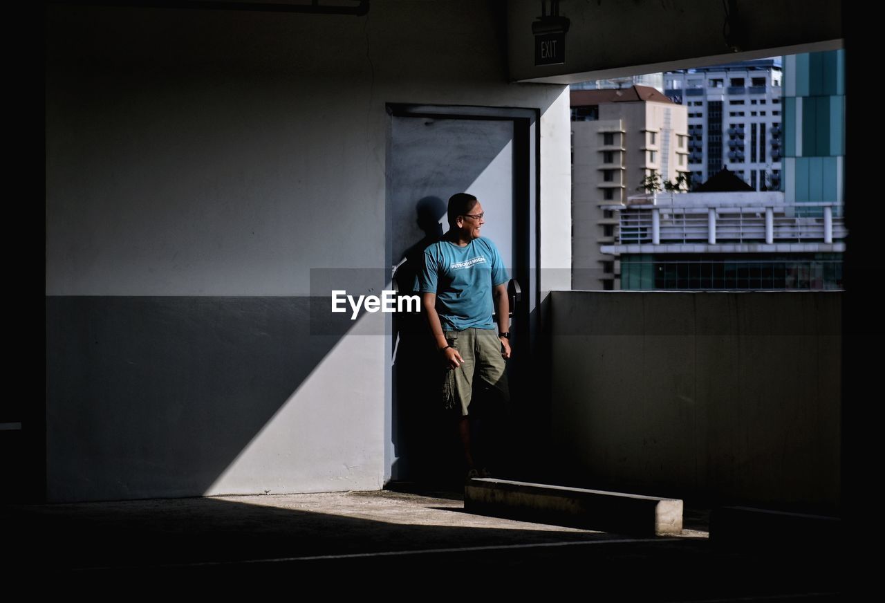 MAN STANDING BY BUILDING IN CITY