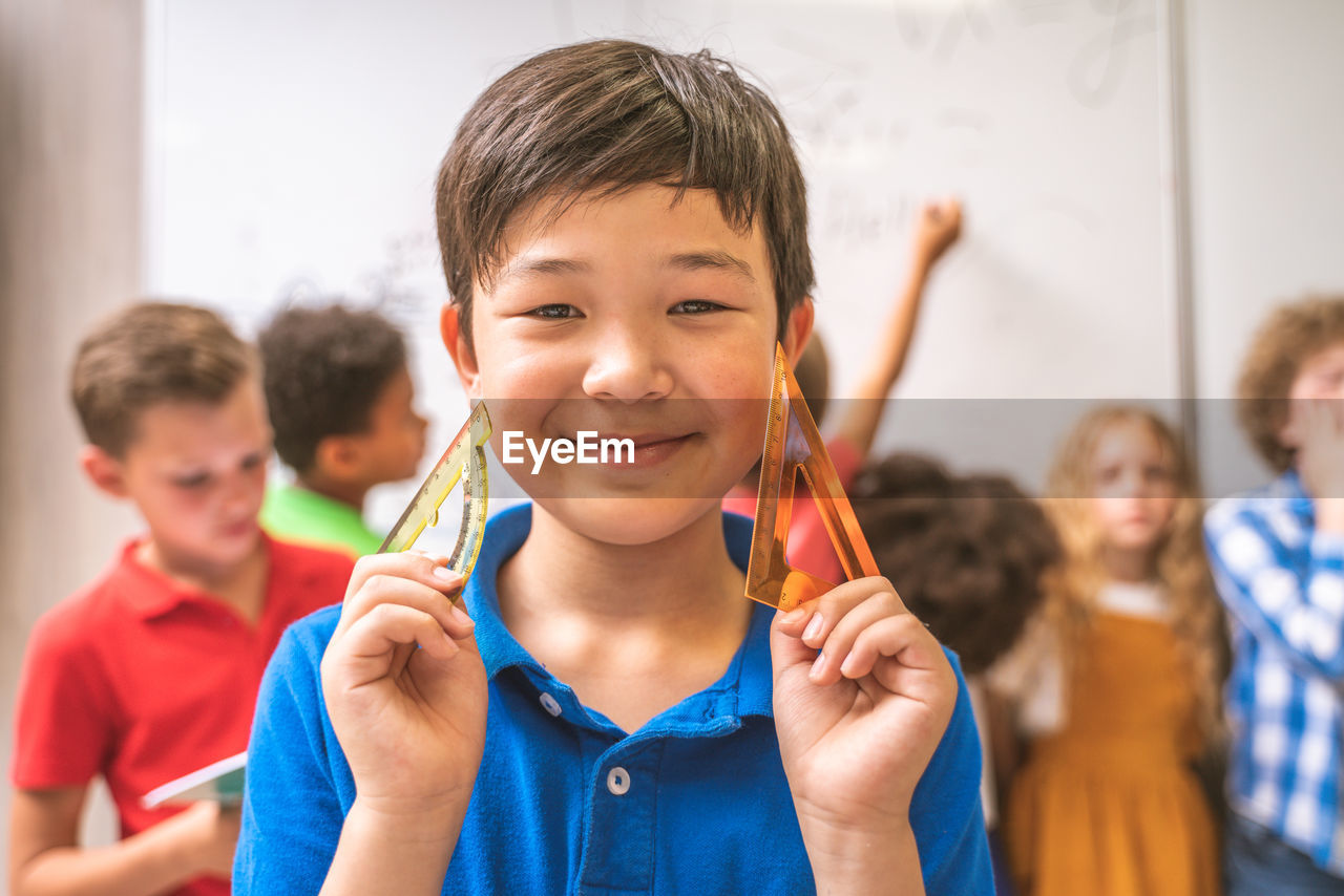 Portrait of cute boy holding ruler in classroom