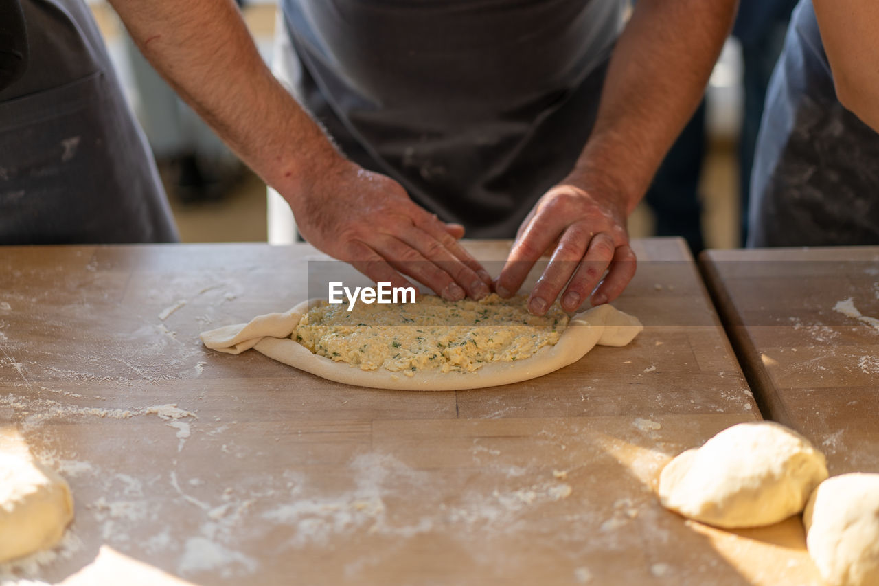 MIDSECTION OF MAN PREPARING PIZZA