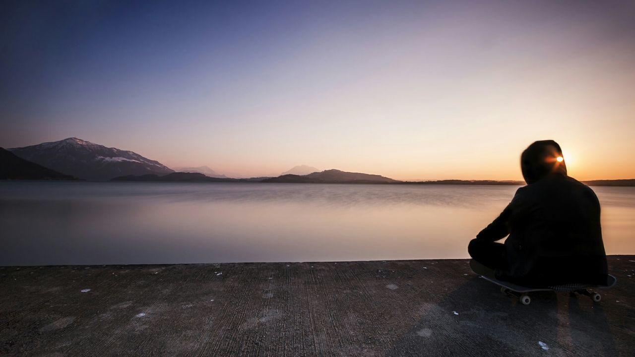 Person sitting on pier against sea