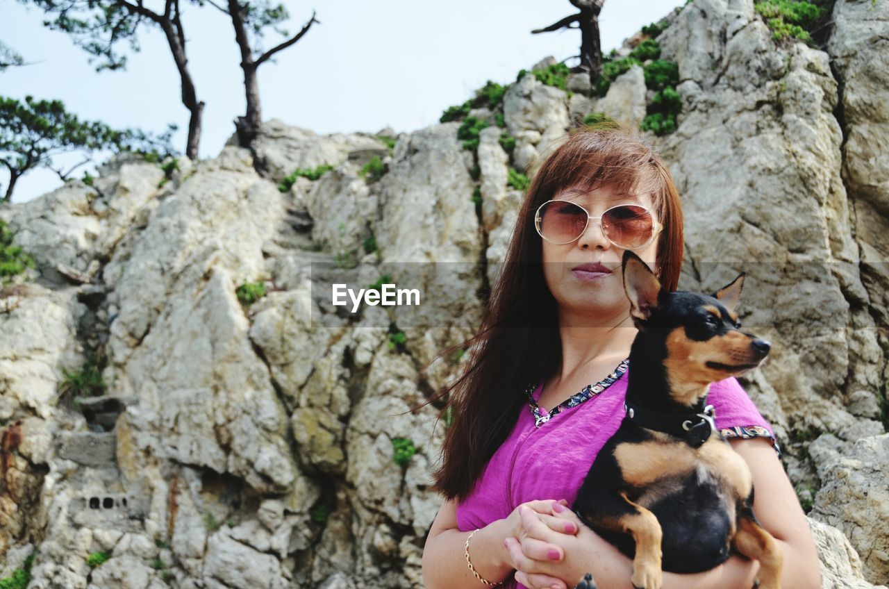 Portrait of woman carrying dog outdoors