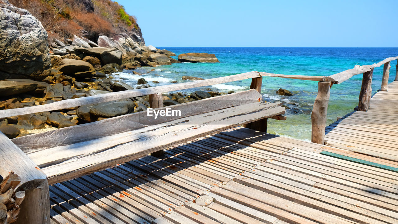 Wooden seat at dock beside the sea landscape background.