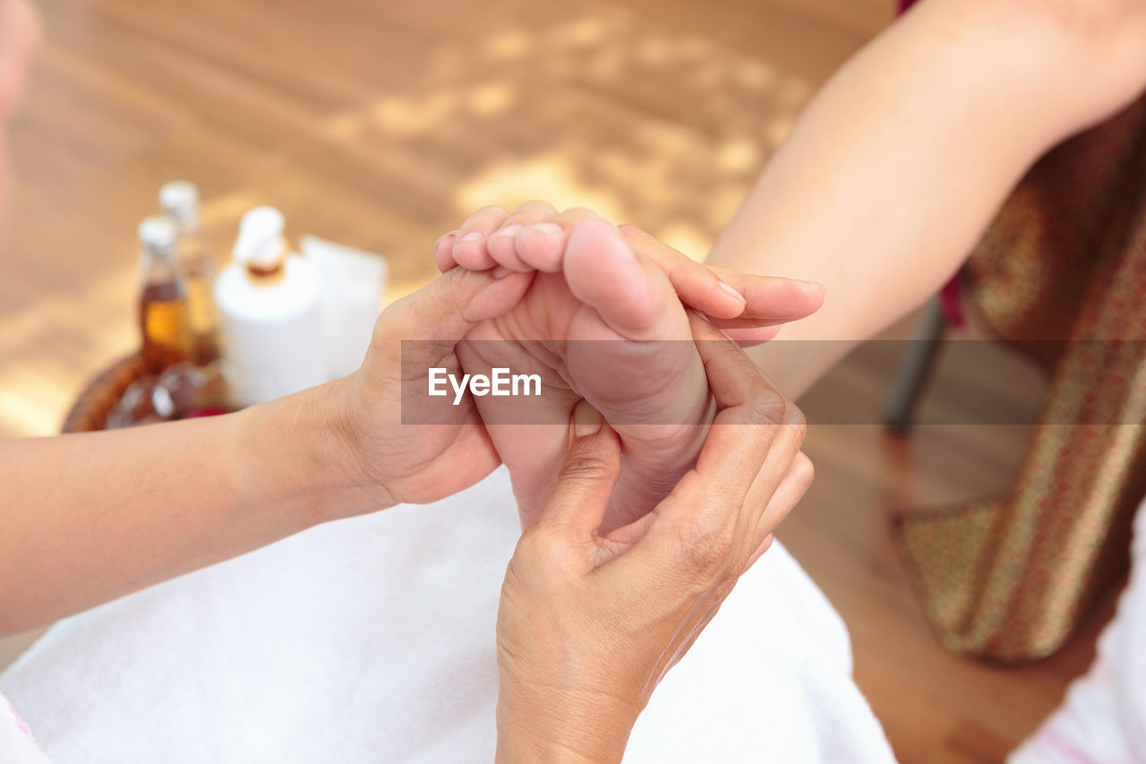 Cropped image of woman giving feet massage to customer