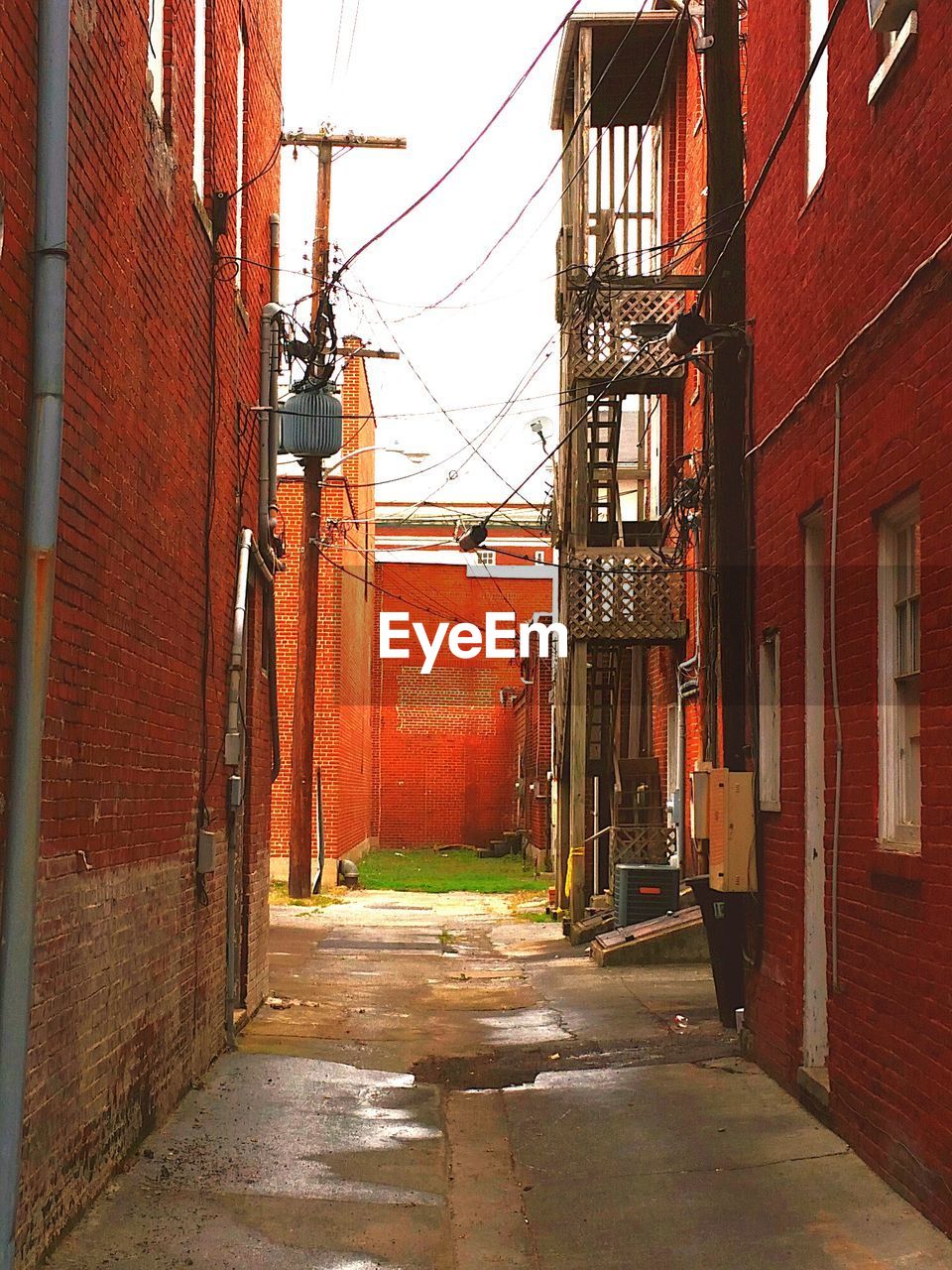 Empty alley amidst red brick wall houses