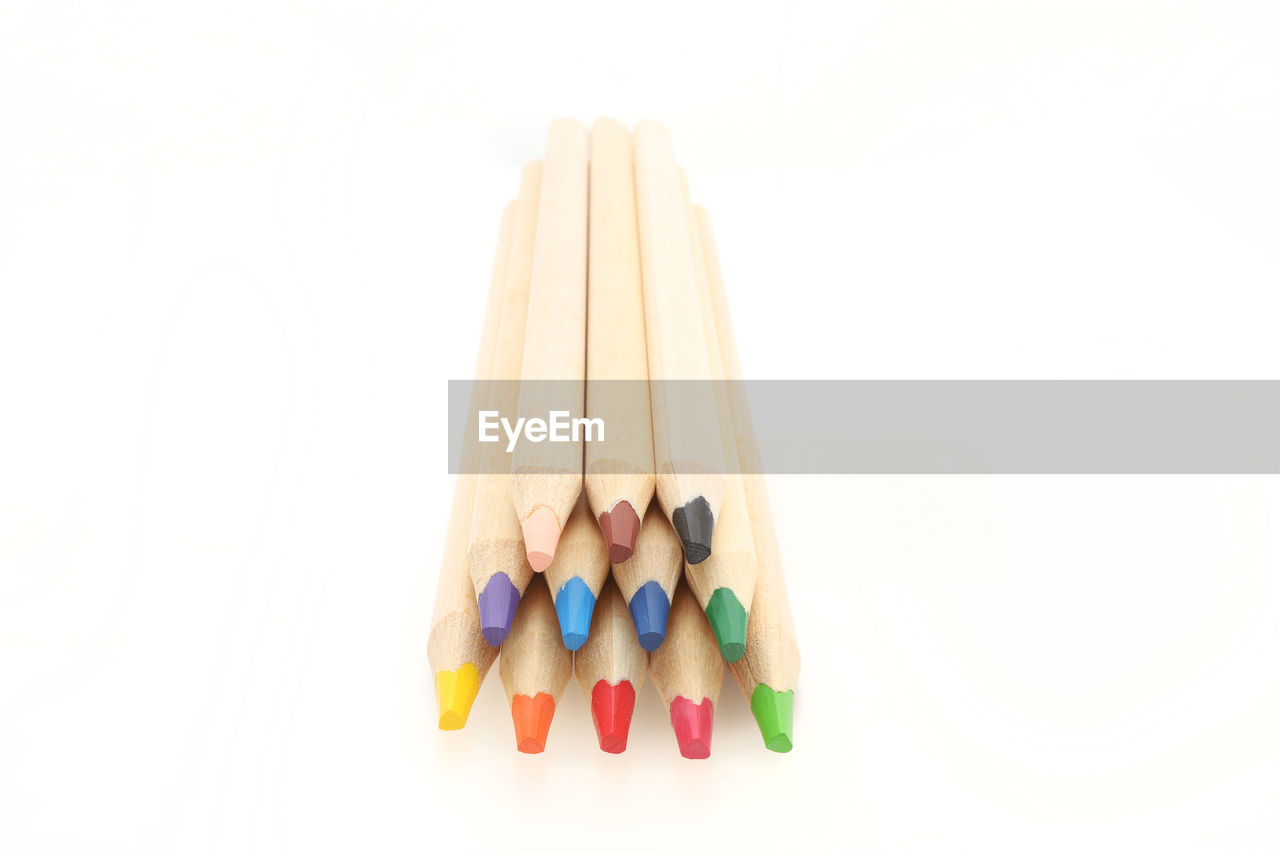 CLOSE-UP OF COLORED PENCILS OVER WHITE BACKGROUND