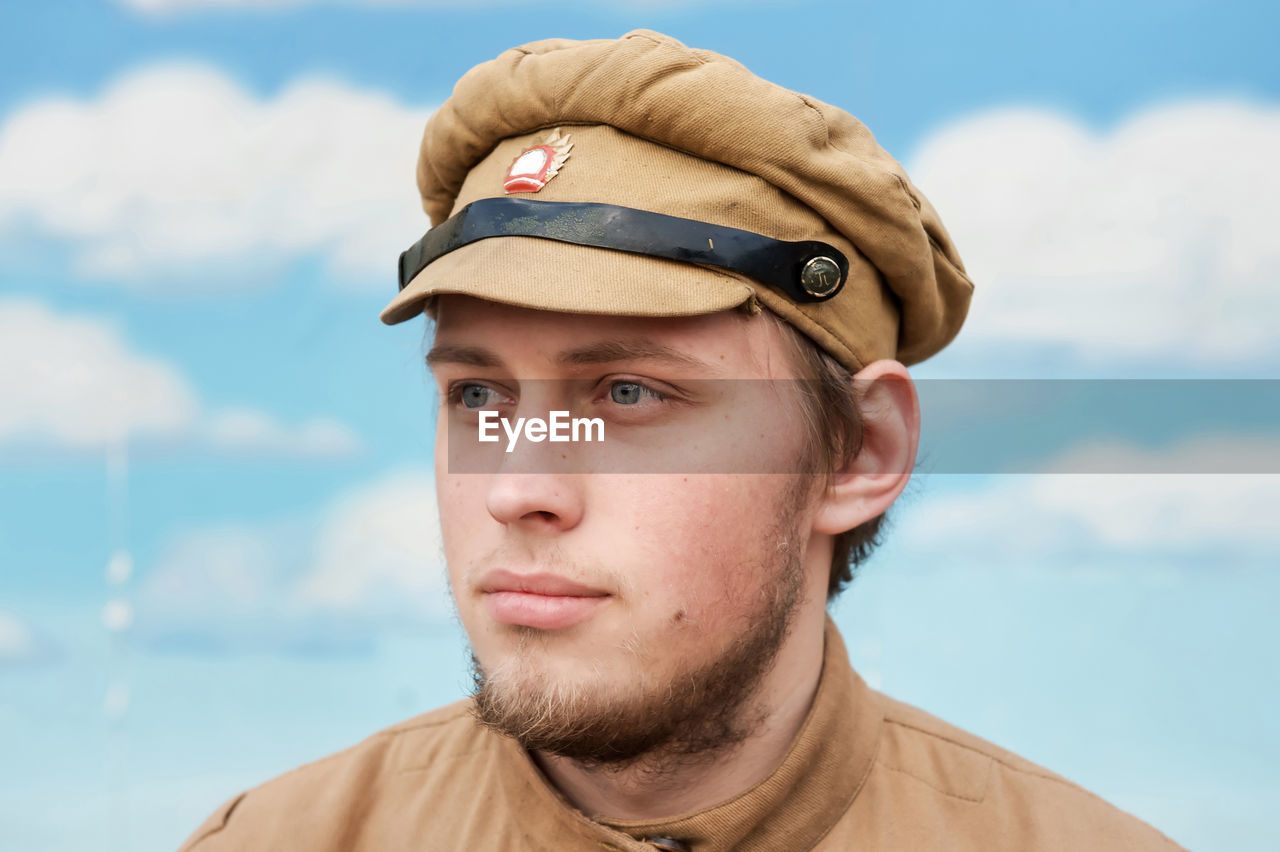 Young man wearing costume looking away against sky