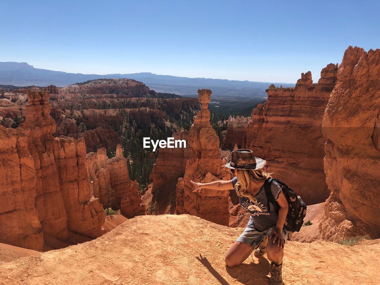 Woman gesturing towards rock formation at bryce canyon