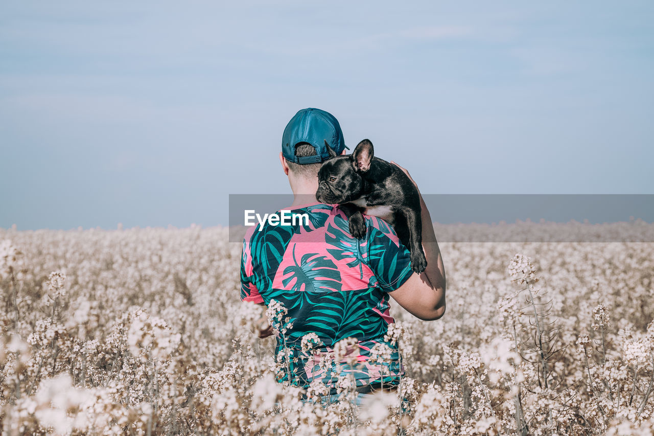 Man with dog standing by blooming flowers