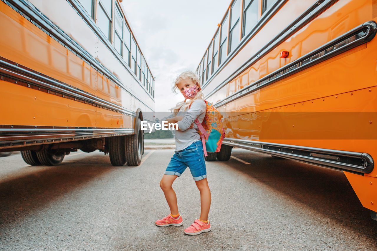 Portrait of girl standing against bus
