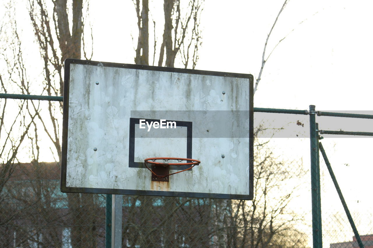 Old basketball hoop against sky