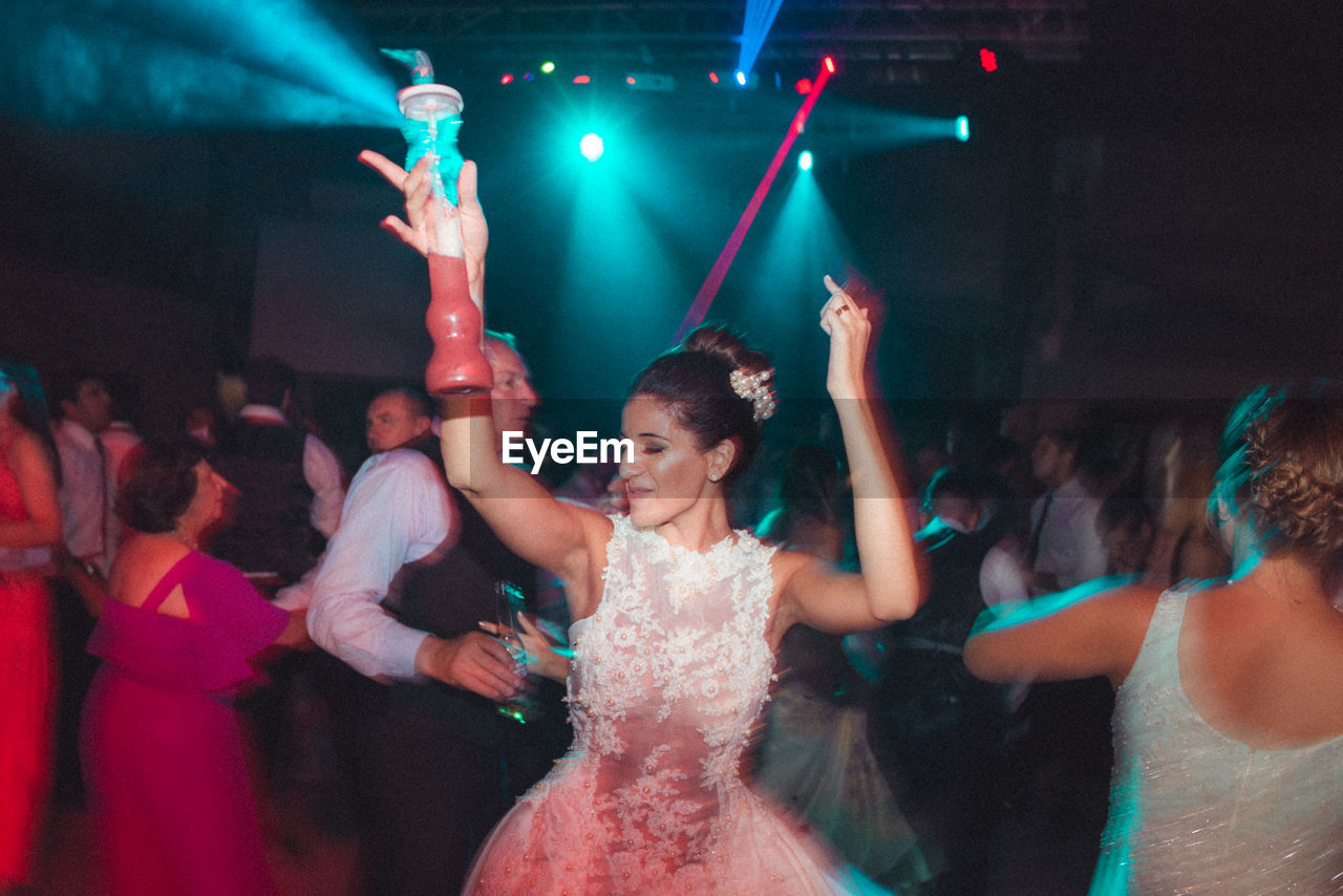 GROUP OF PEOPLE DANCING AT NIGHTCLUB