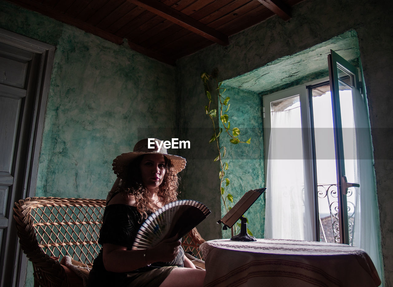 WOMAN SITTING ON CHAIR AT HOME