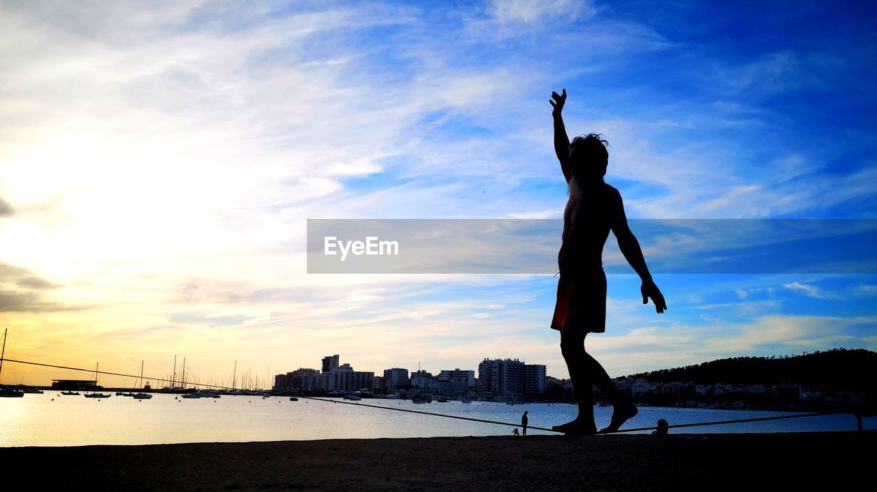 SILHOUETTE WOMAN WITH ARMS RAISED AT SUNSET