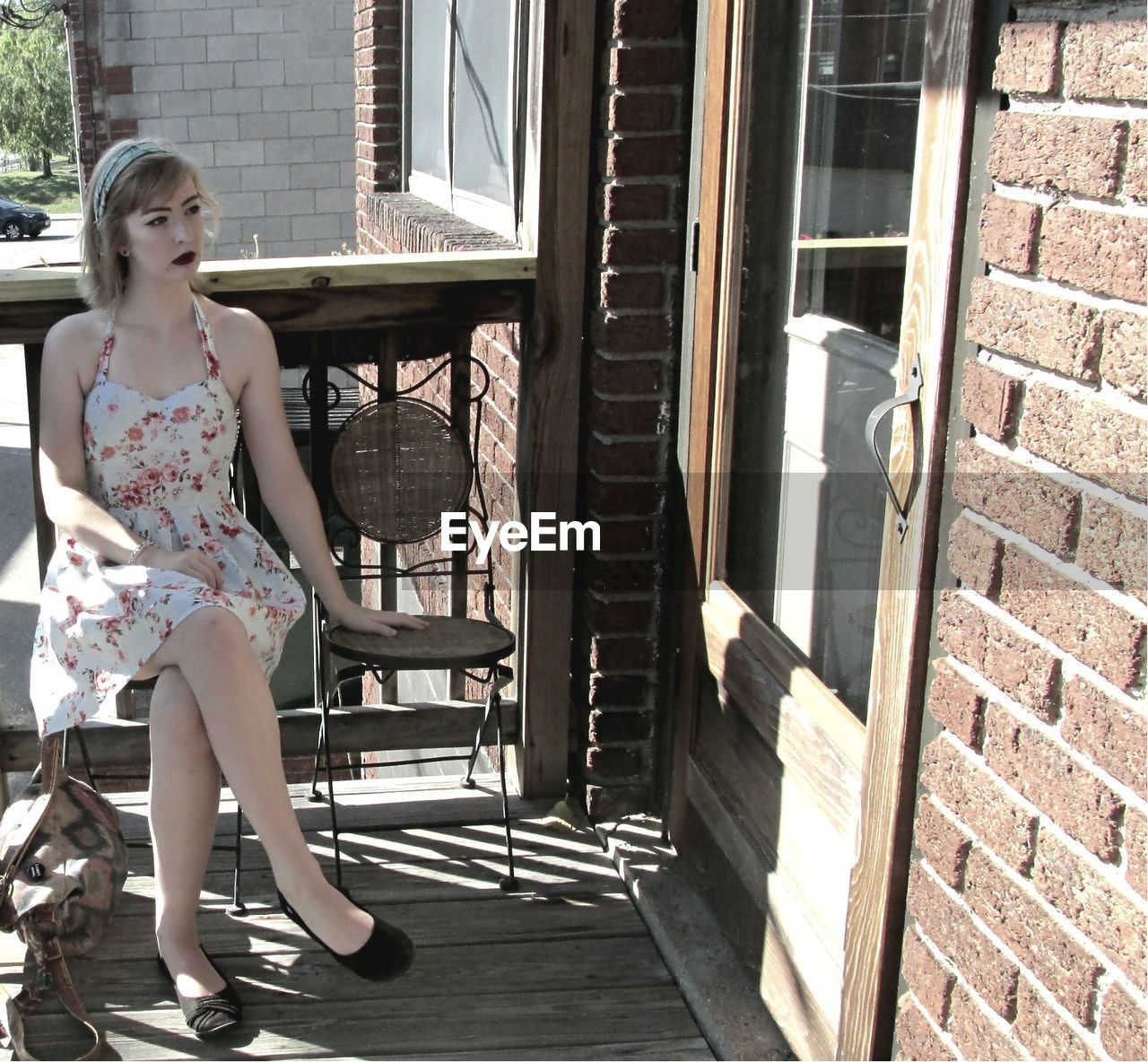 YOUNG WOMAN STANDING BY WINDOW ON BUILDING