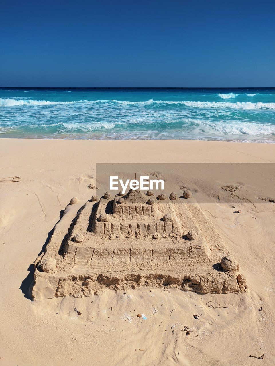 Sand castle at beach against clear sky