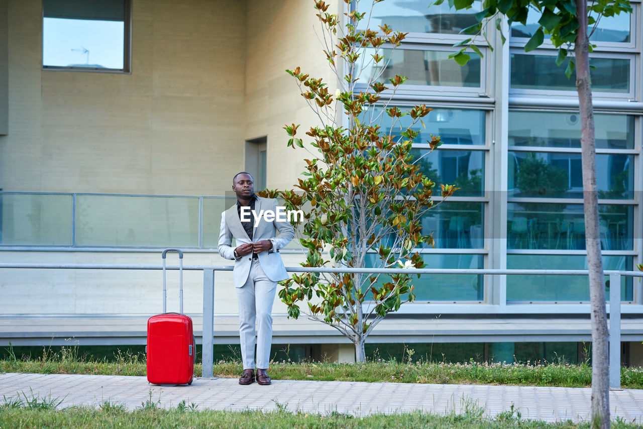African-american in a white suit and a red suitcase. person