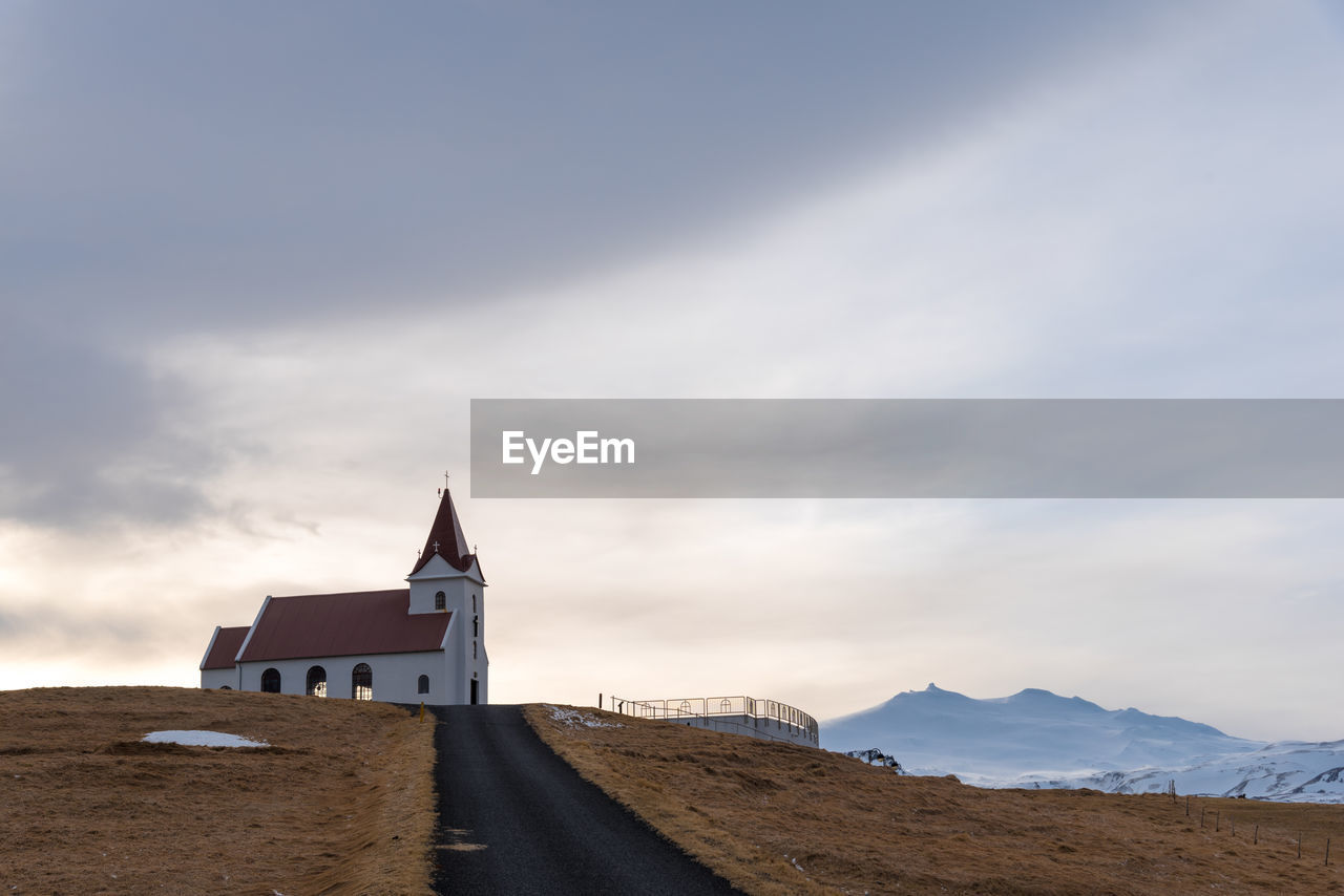 VIEW OF BUILDING BY MOUNTAIN AGAINST SKY