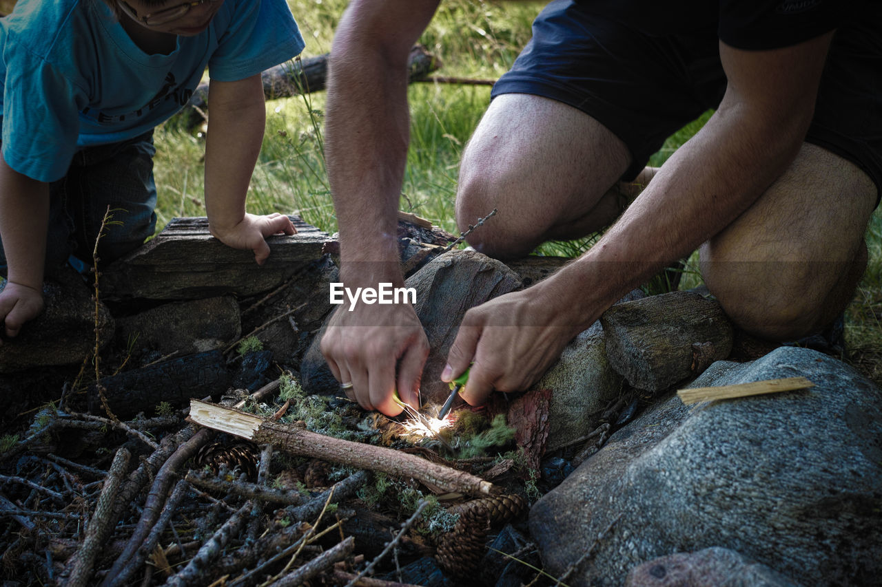 Cropped image of father and boy burning firewood