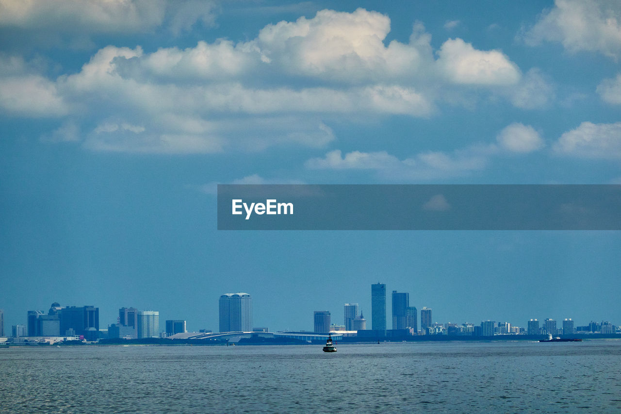 Sea by buildings against sky