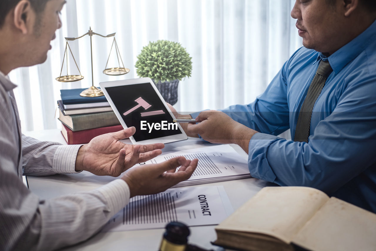 MIDSECTION OF MAN AND WOMAN SITTING ON TABLE AT HOME