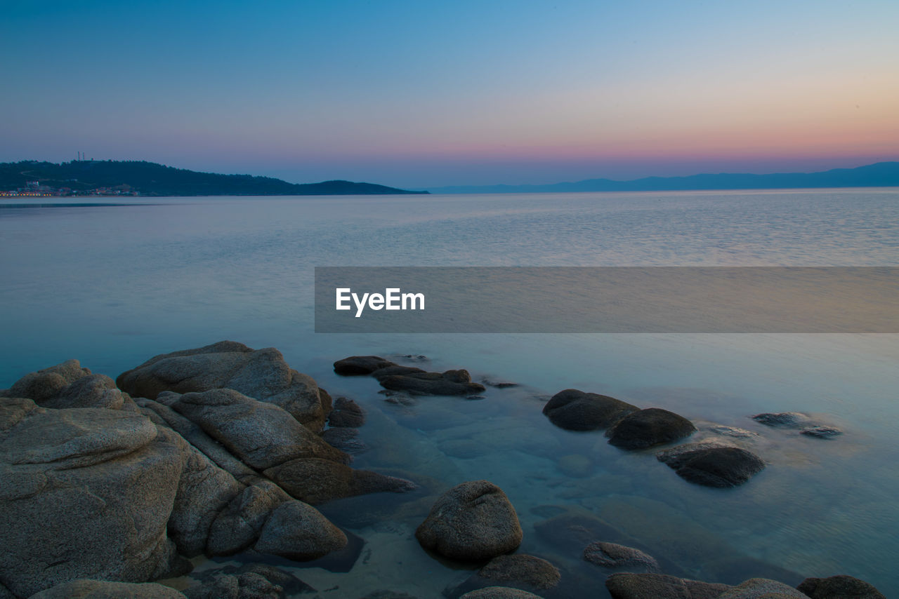 ROCKS IN SEA AGAINST SKY DURING SUNSET