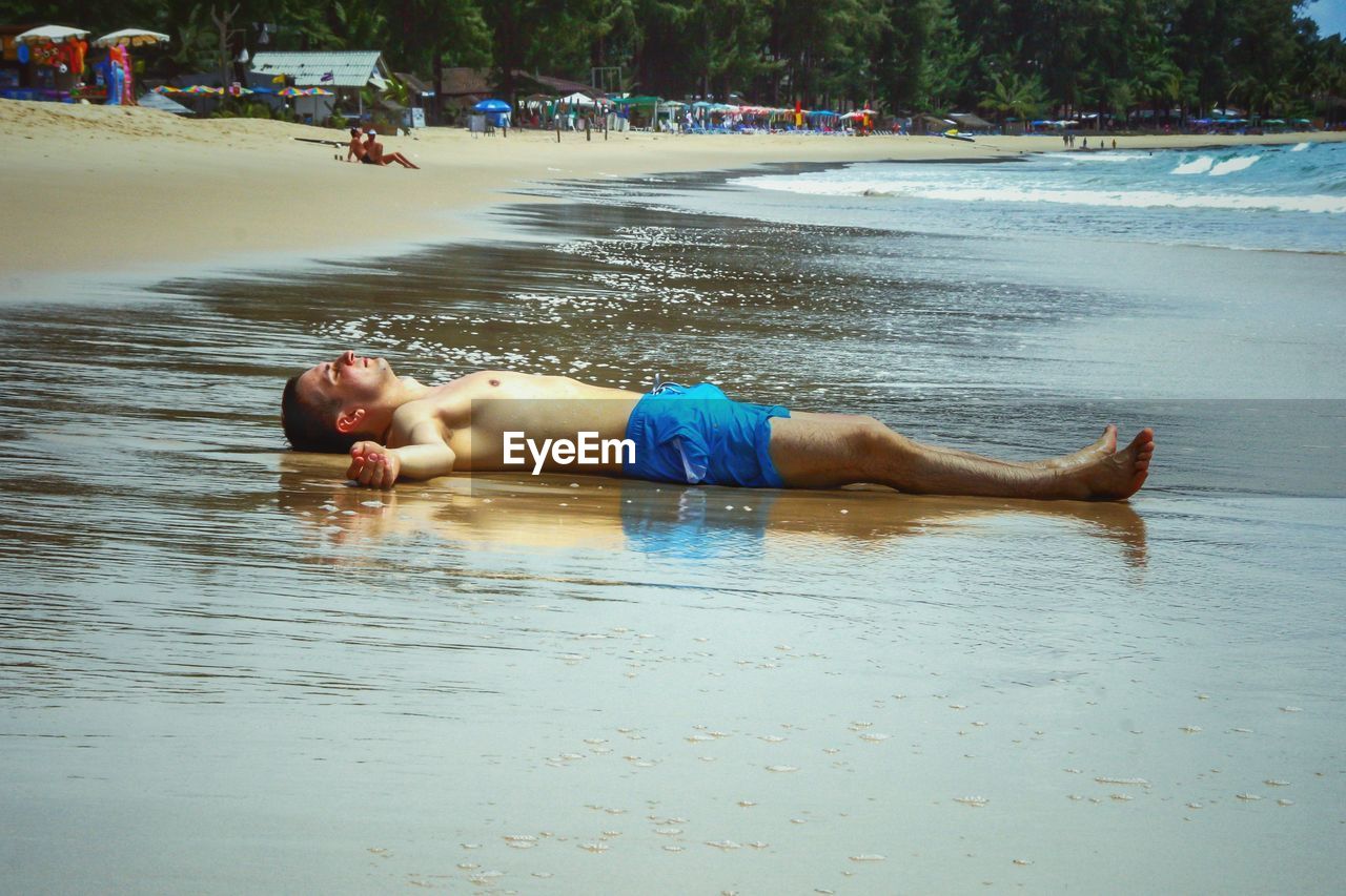 Man lying on wet shore
